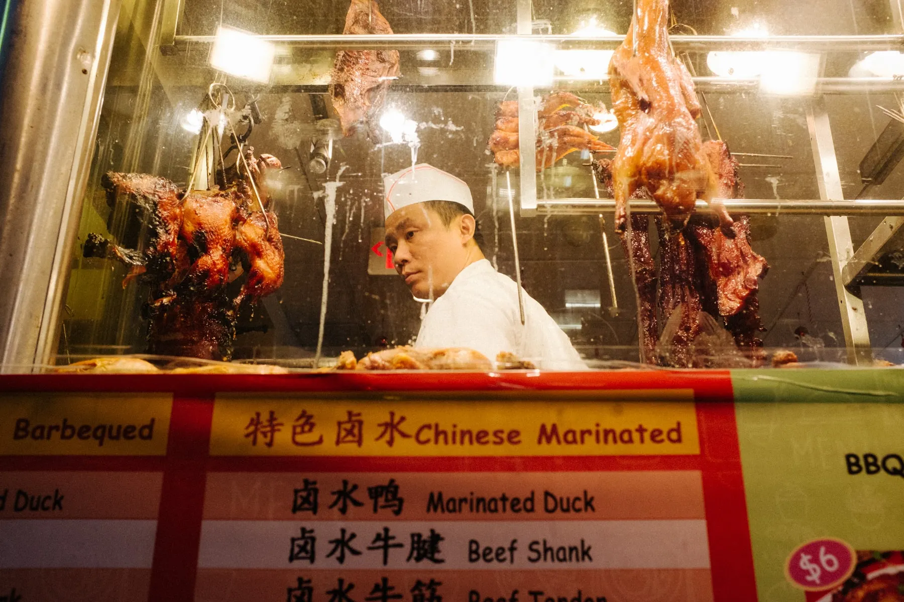 Cook behind glass in a window hung with roast ducks