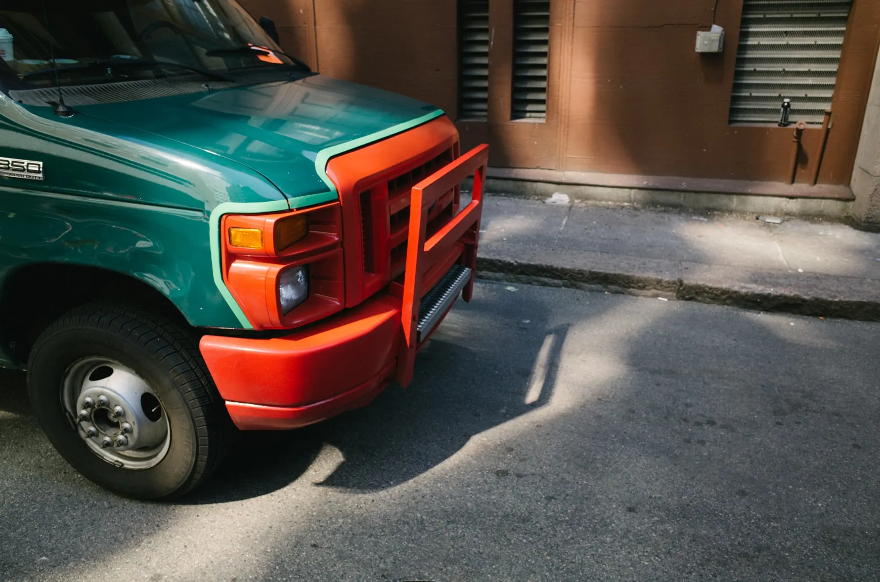 Green van with an orange bull bar parked by a brick wall