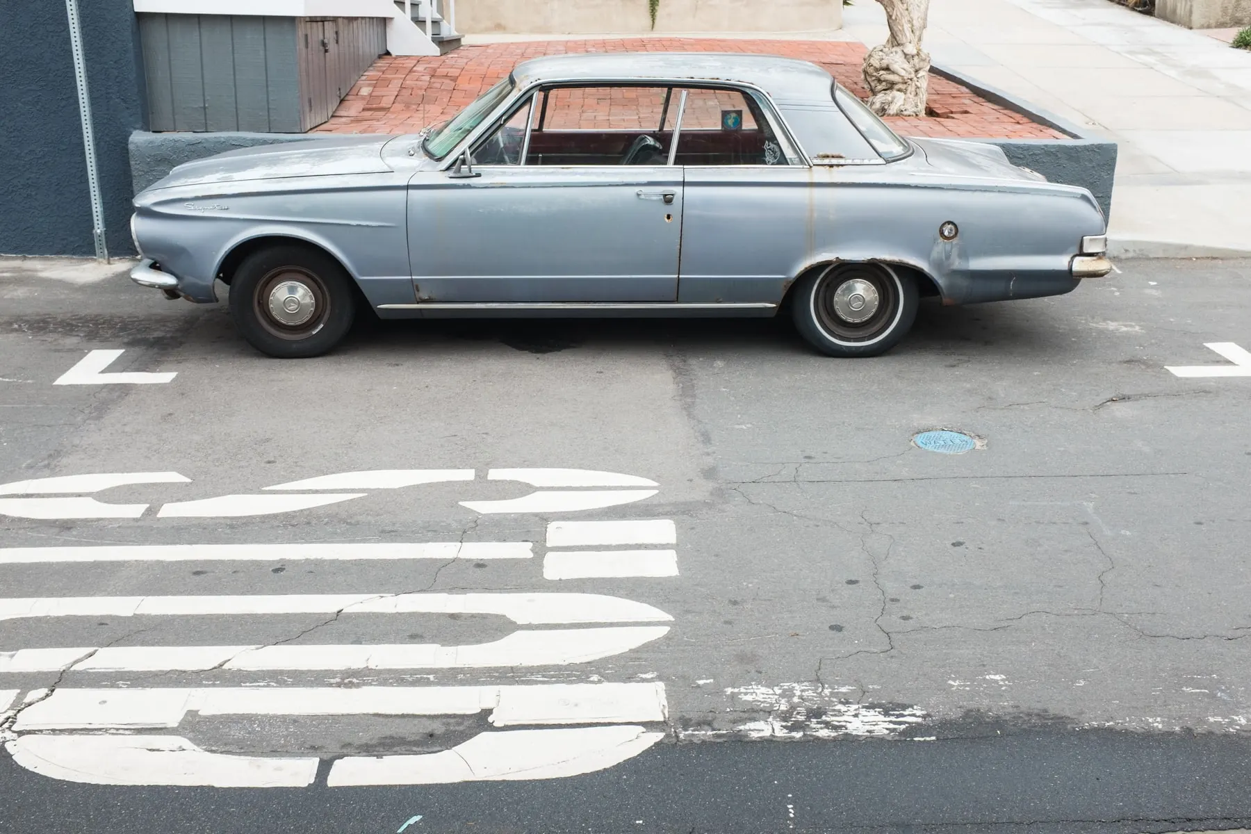 Pale blue coupe parked over faded road lettering