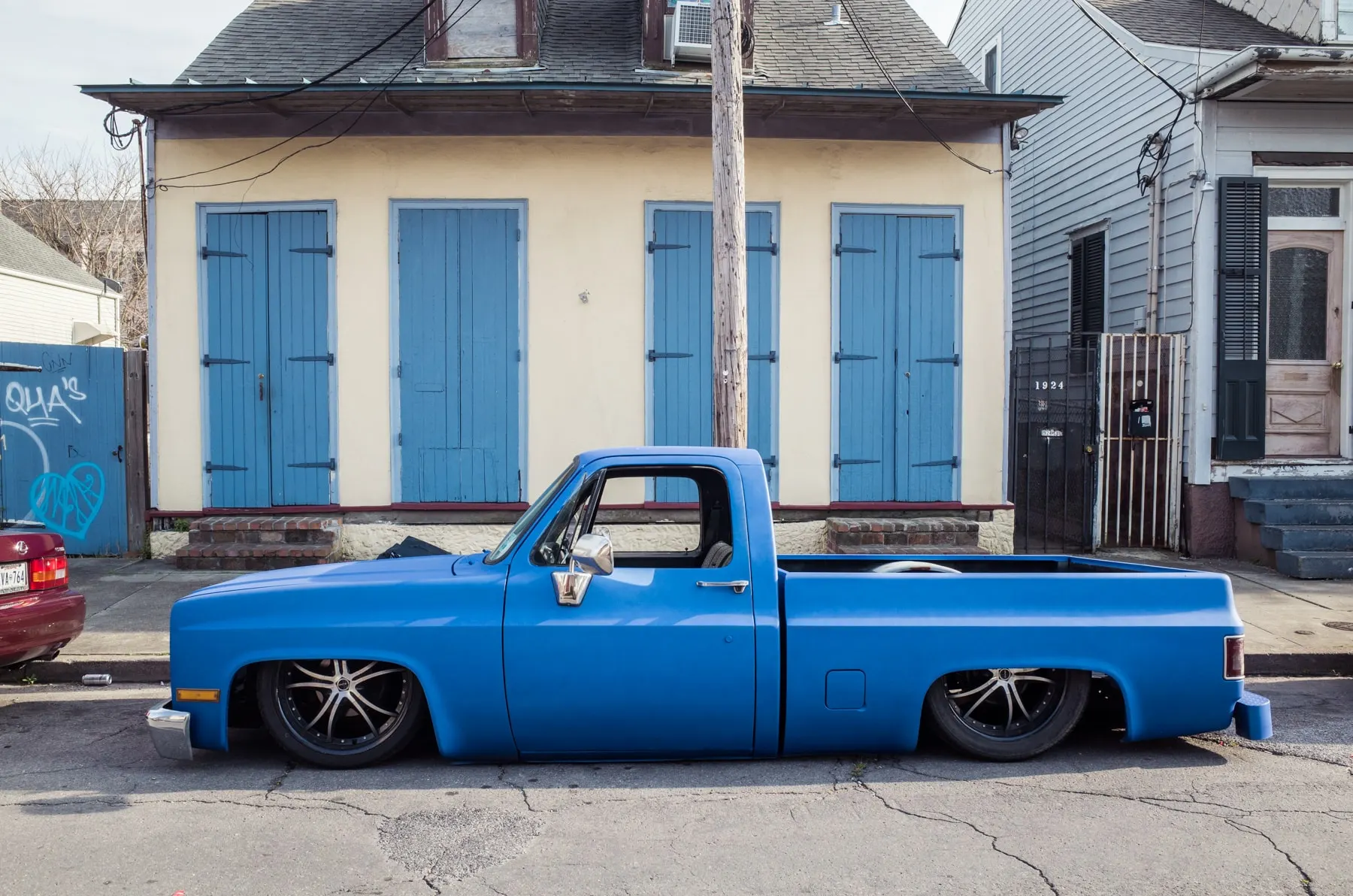 Lowered blue pickup outside a house with blue shutters