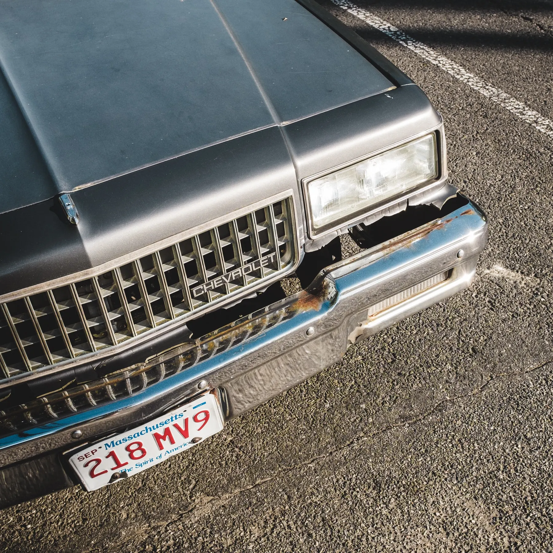 Front of an old Chevrolet with a dented chrome bumper