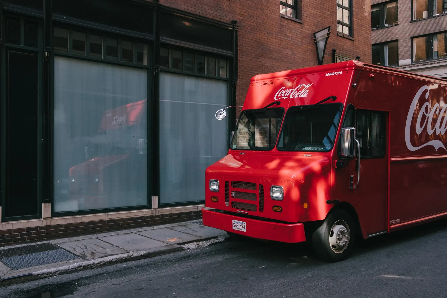 Red Coca-Cola delivery truck parked on a sloping street