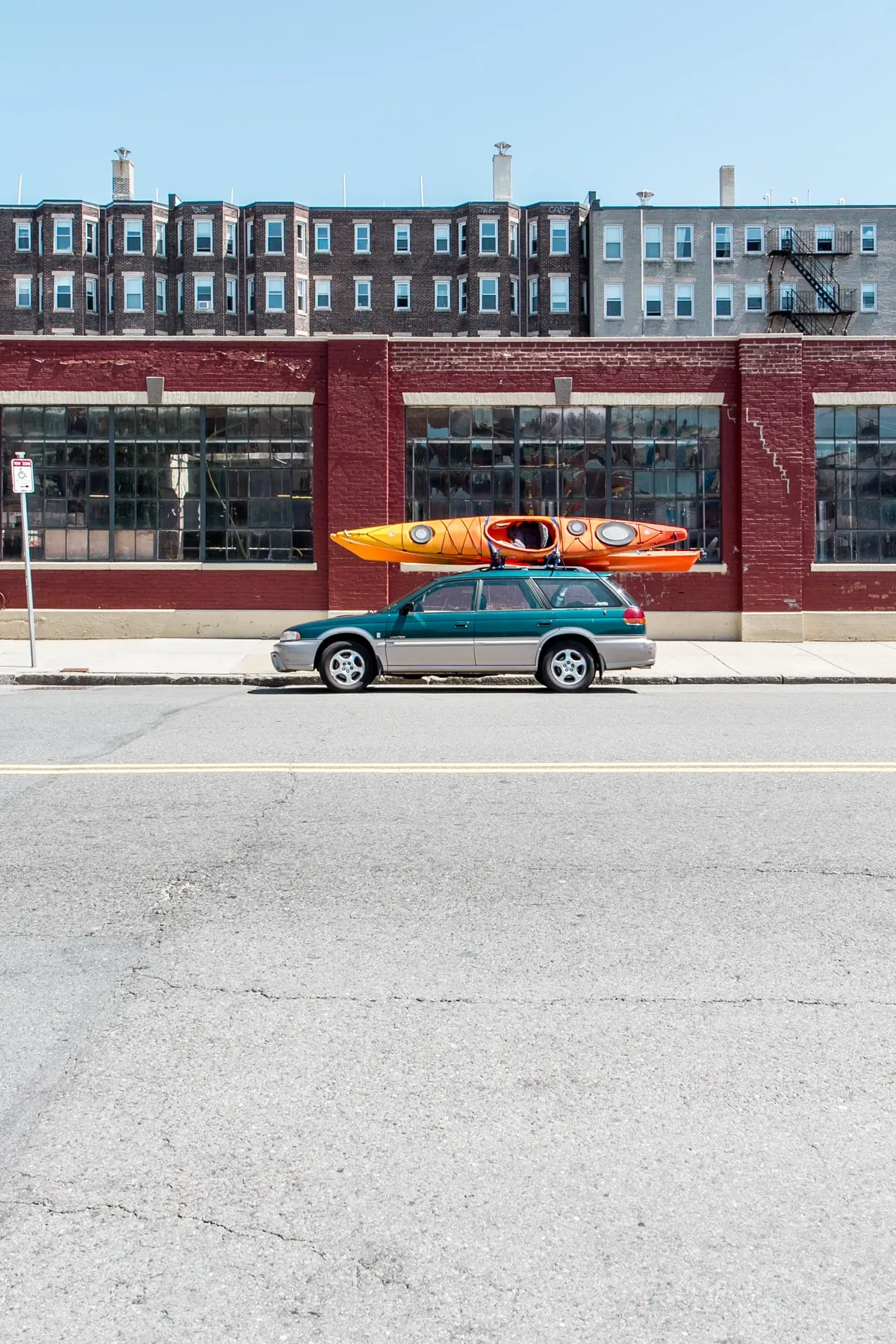 Estate car with kayaks on the roof outside a red brick building