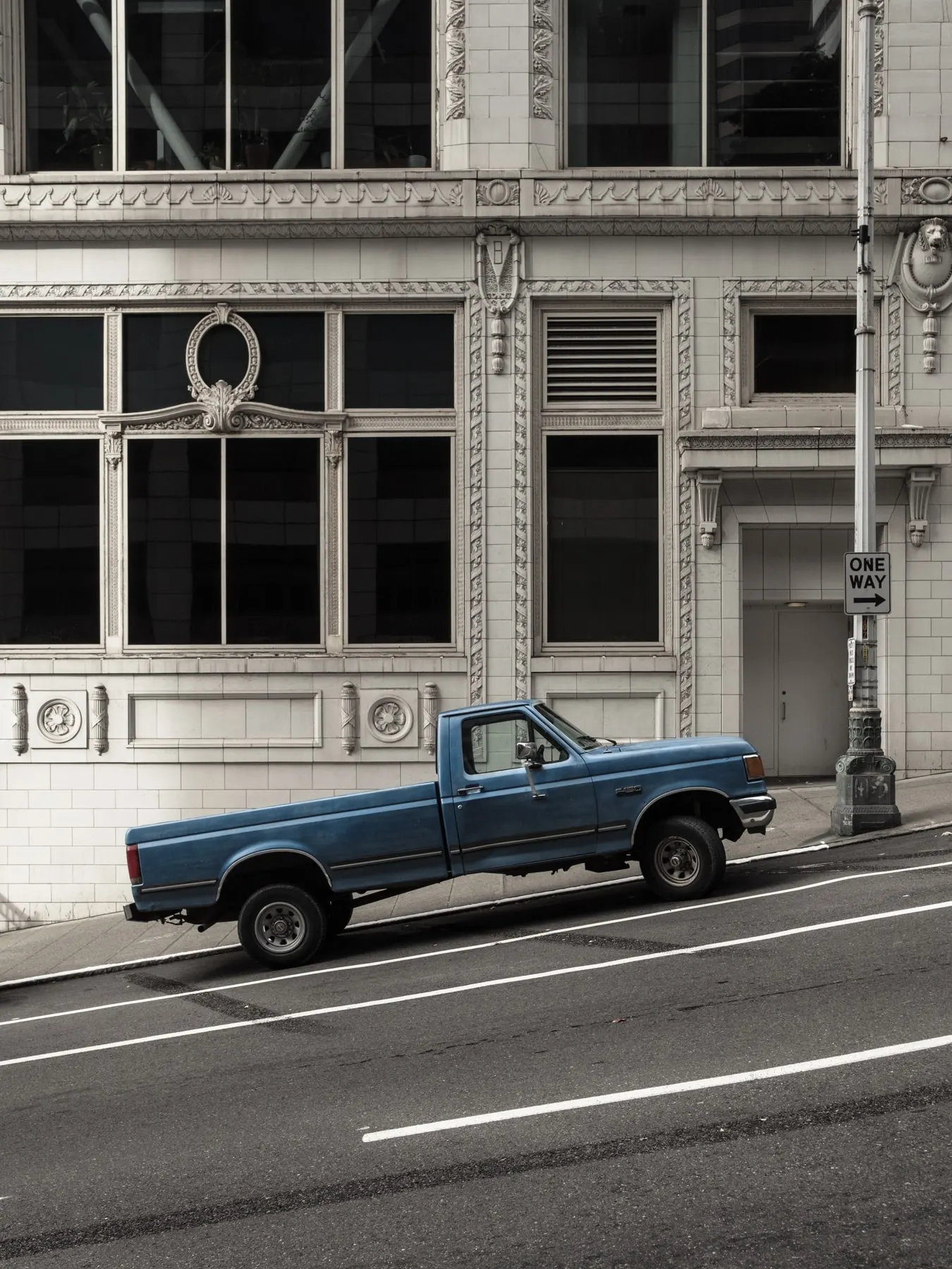 Blue pickup parked below an ornate white building