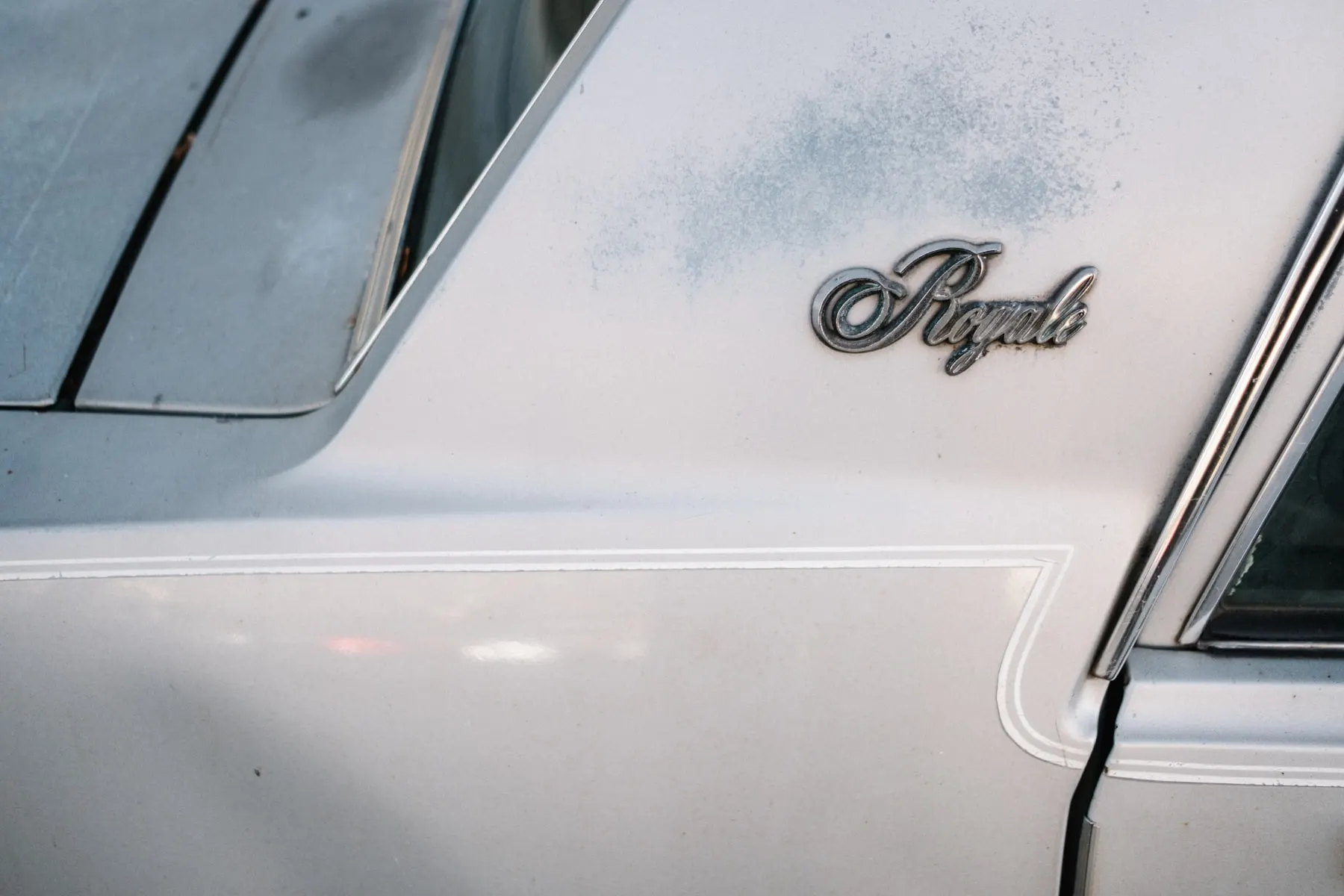 Chrome Royale badge on the white flank of an old car