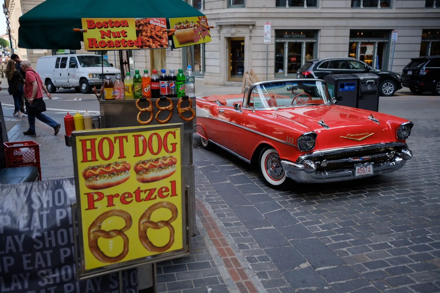 Red convertible parked beside a hot dog and pretzel cart