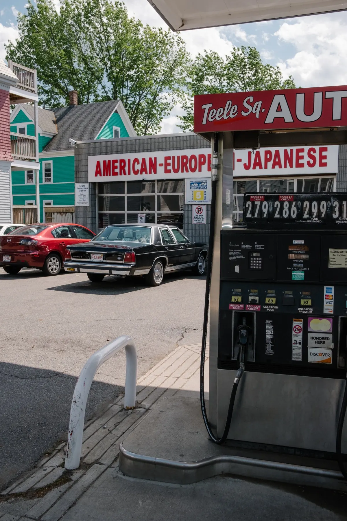 Pumps at a corner garage advertising American, European and Japanese repairs