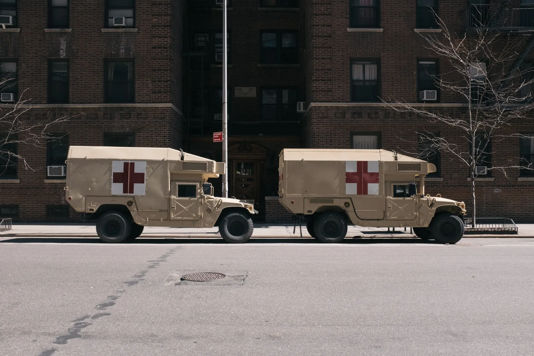 Two military ambulances parked outside an apartment block