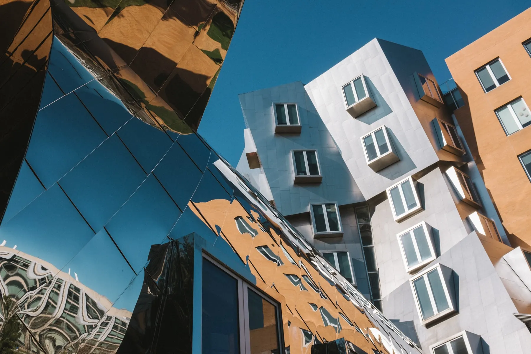 Mirrored and angled facades of a modern campus building against blue sky