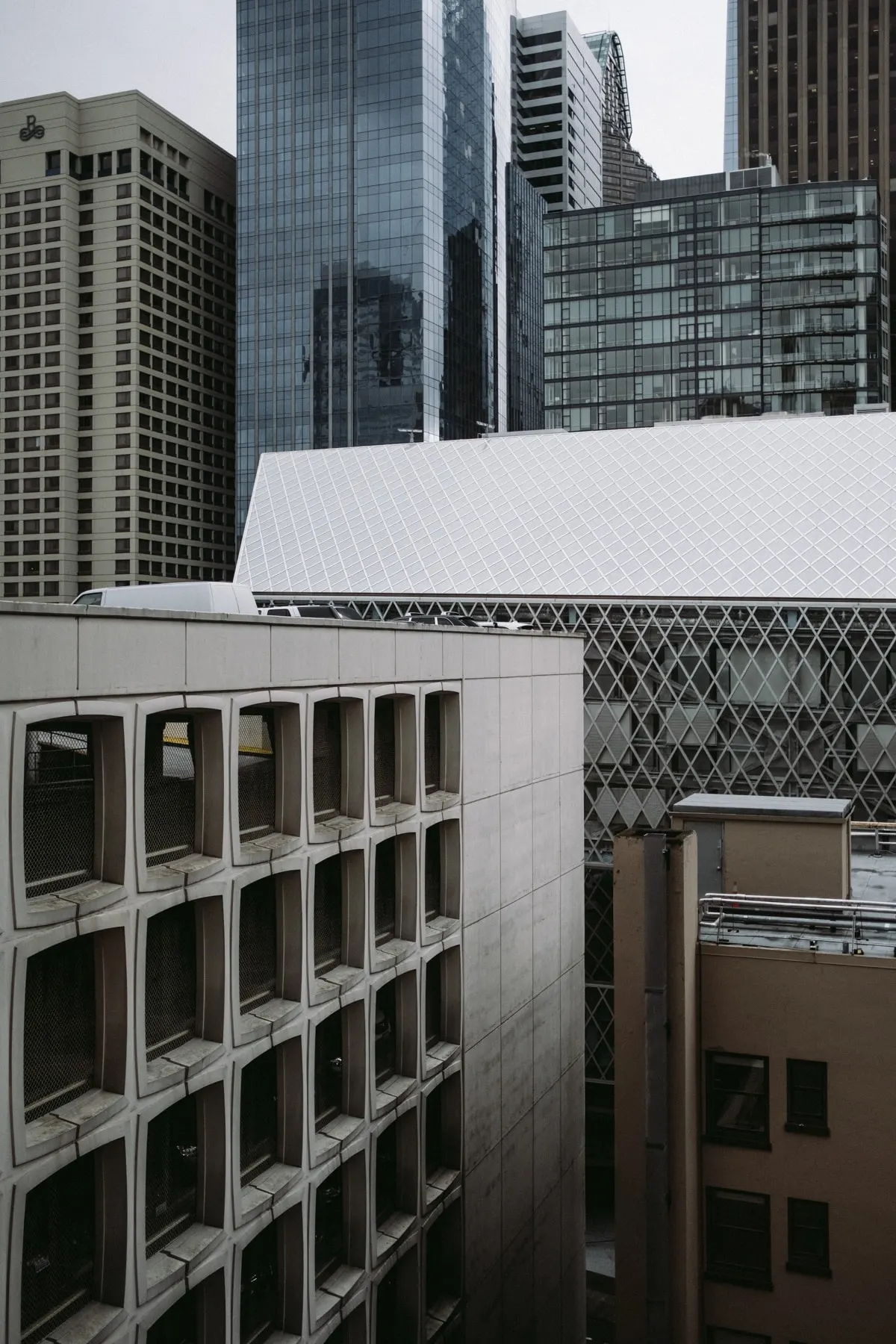 Concrete grid facade below a cluster of glass towers