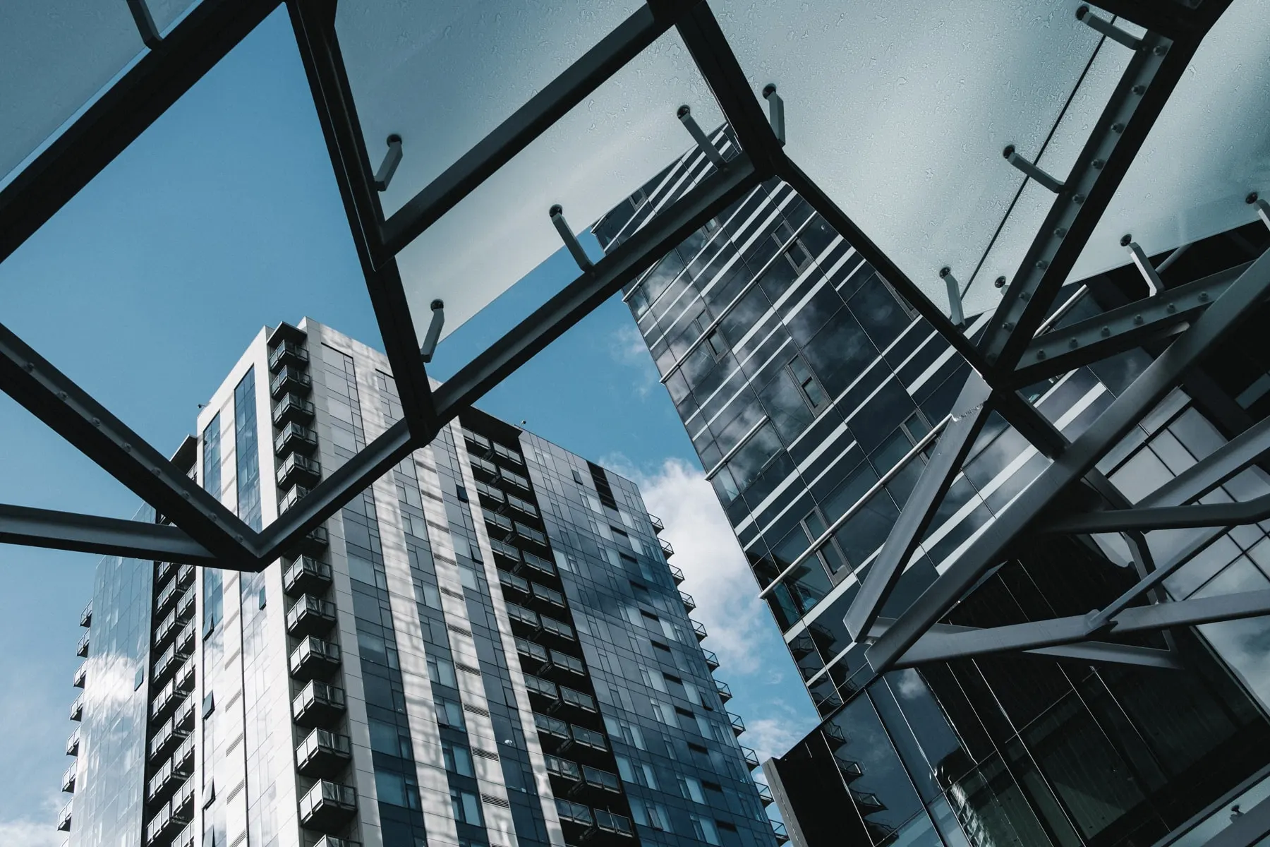 Looking up through a glass canopy at apartment towers