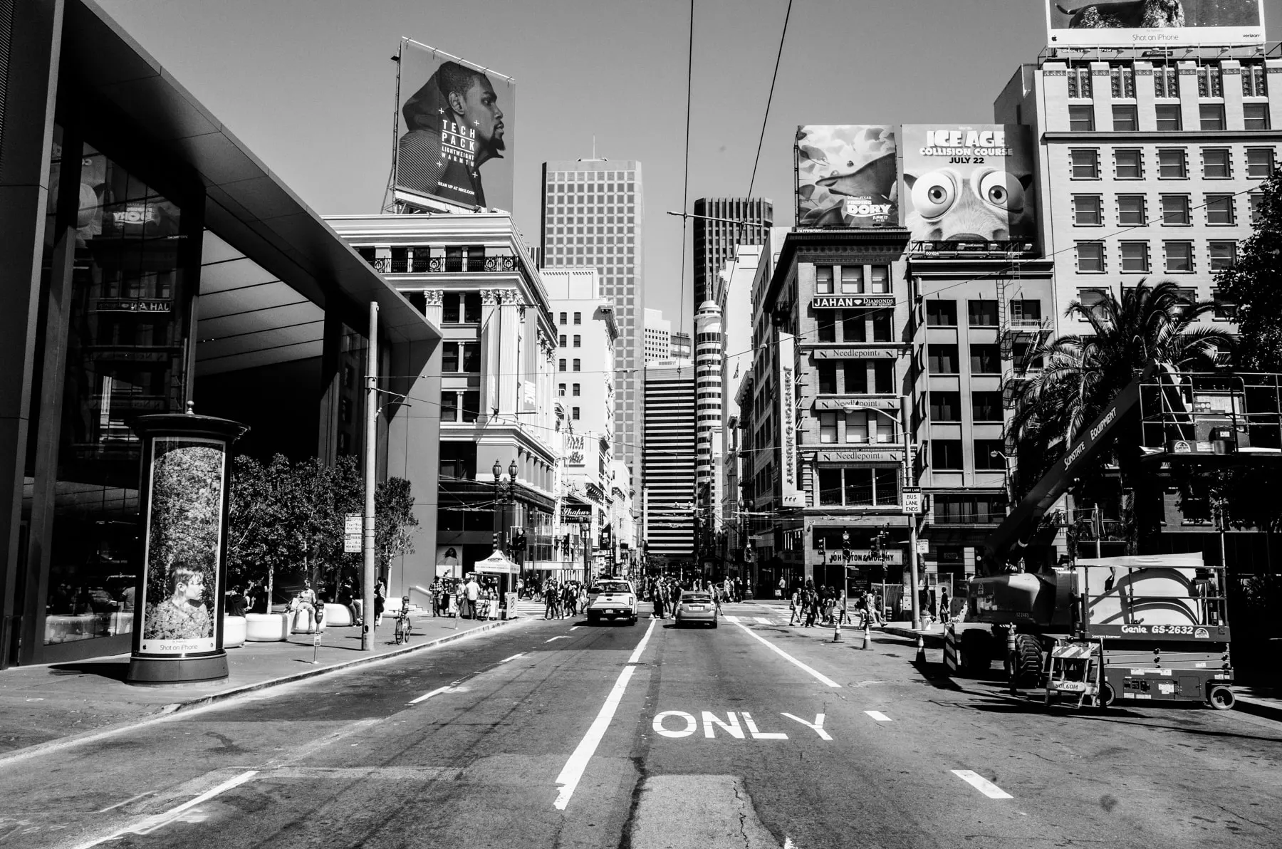 Wide street marked ONLY, billboards and towers along it