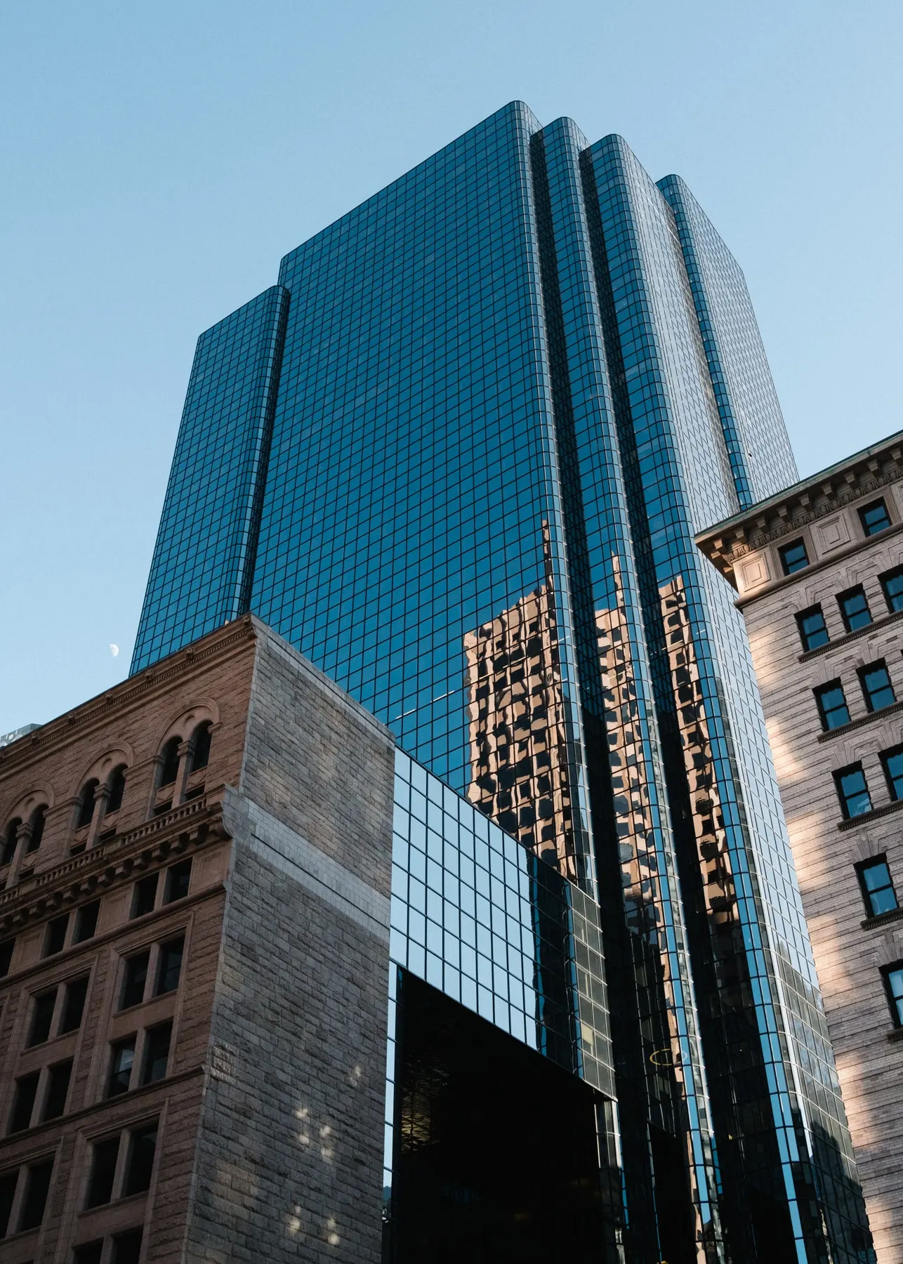 Blue glass tower rising behind stone and brick buildings