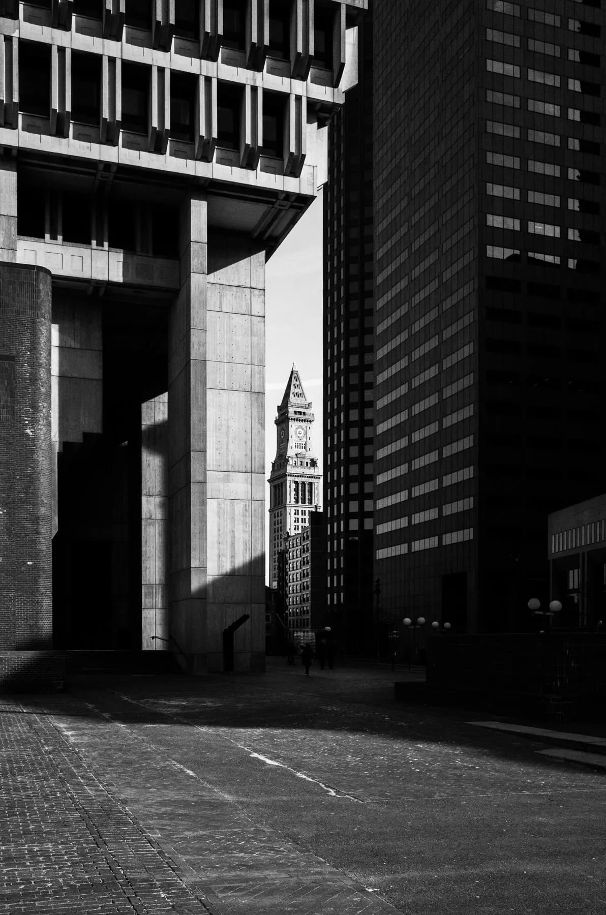 Clock tower framed in a gap between concrete and glass buildings