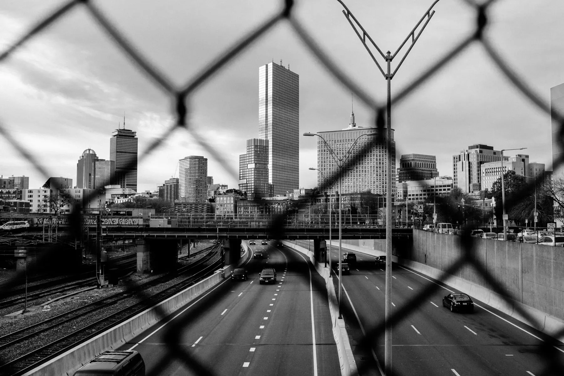 Highway and skyline seen through a chain-link fence