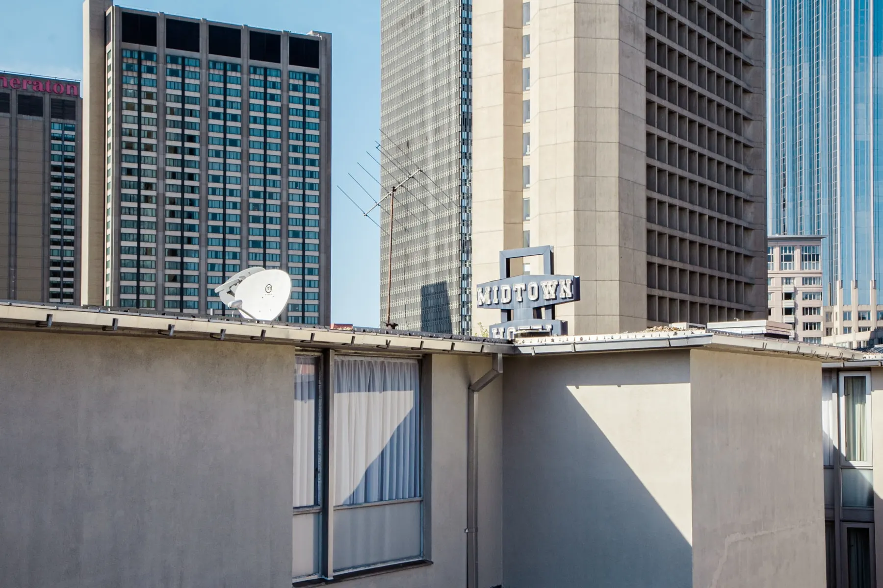 Rooftop with a satellite dish, a Midtown hotel sign behind it