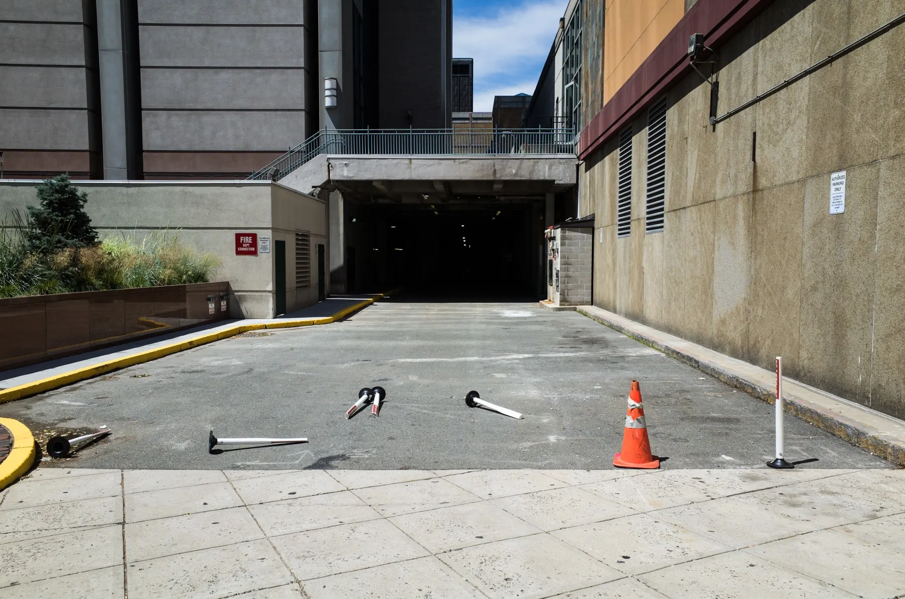 A single cone in an empty concrete driveway beside a garage entrance