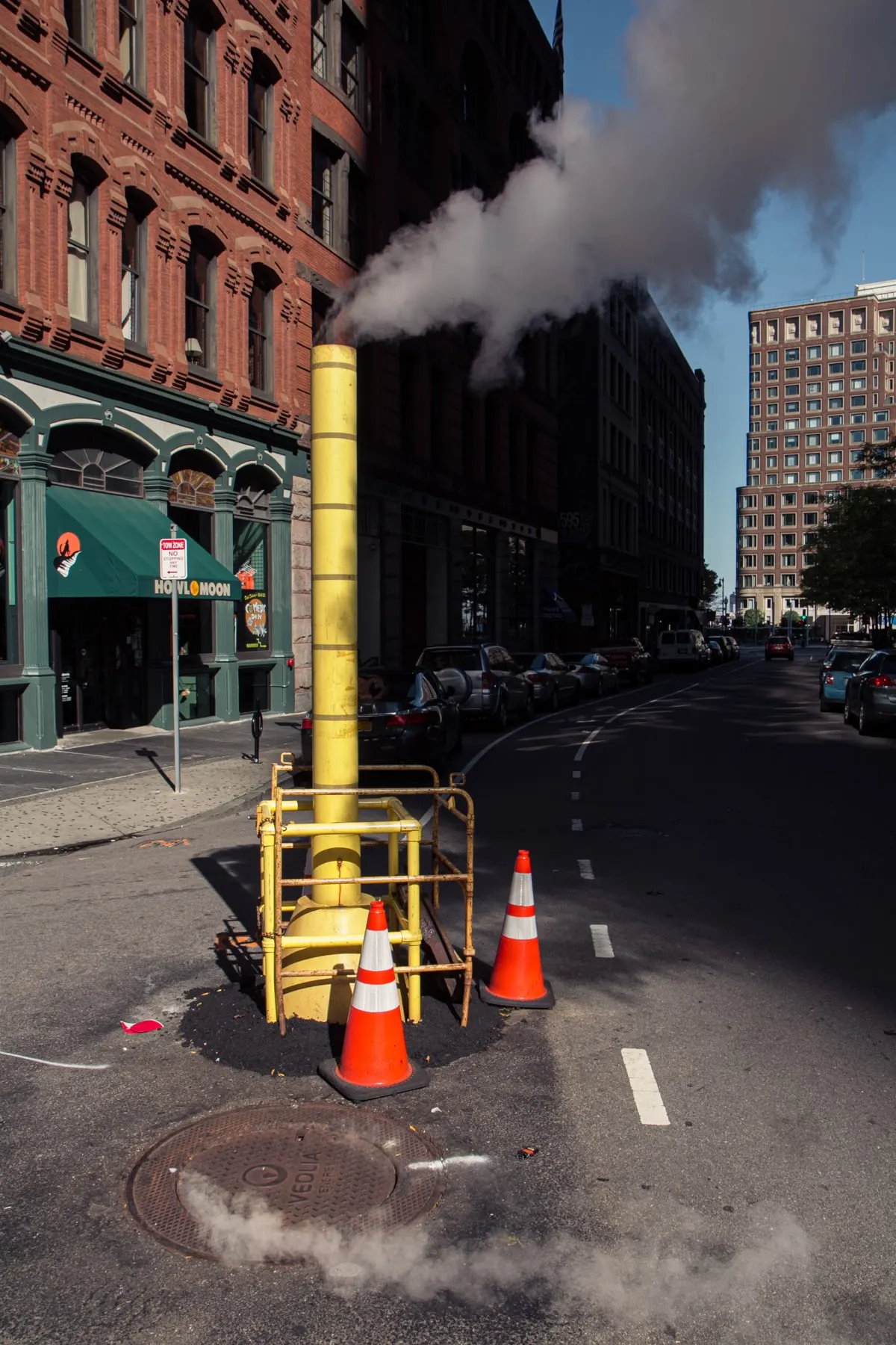 Yellow steam pipe and cones on a street corner