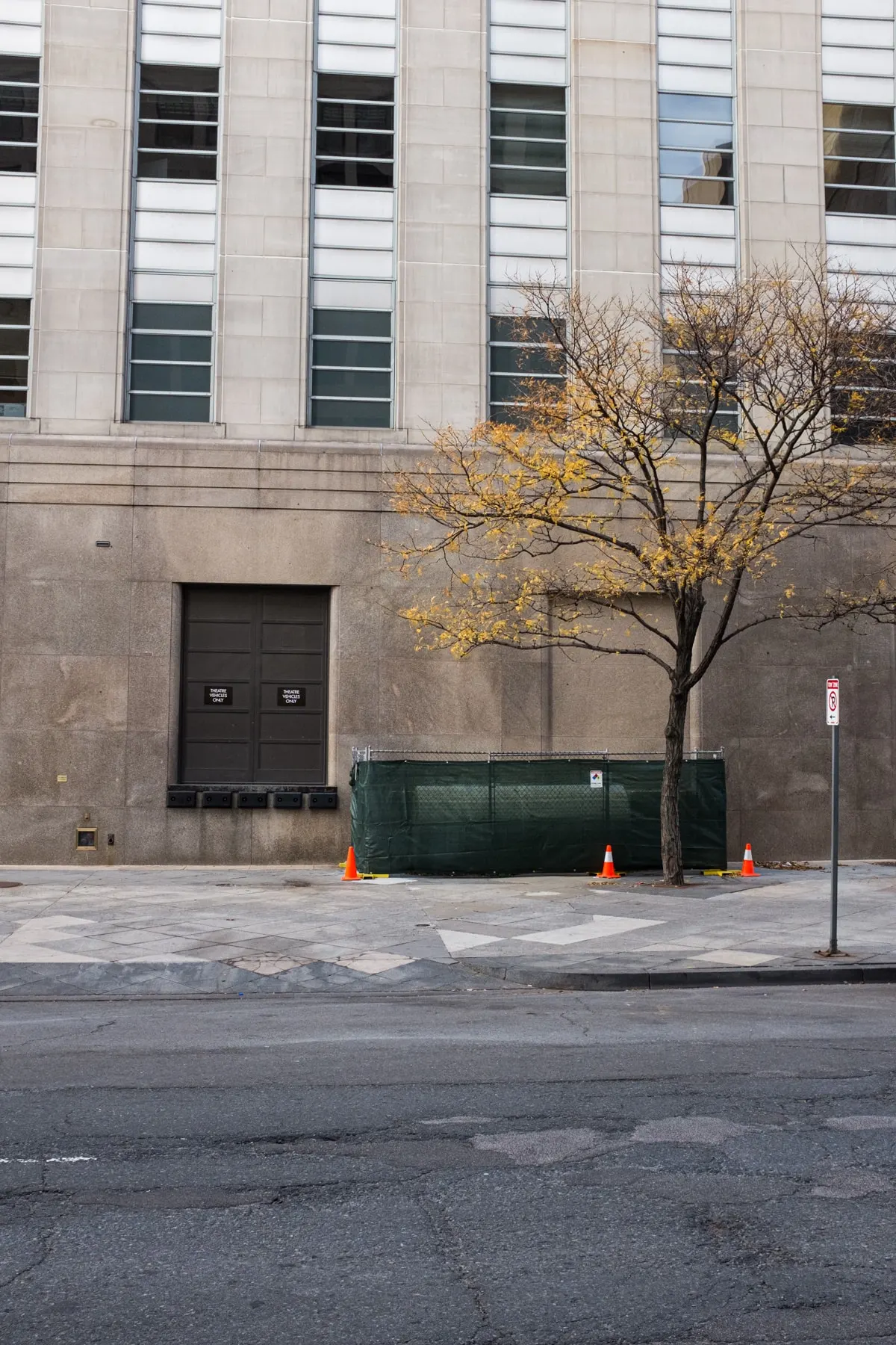 Three cones on a pavement below a large stone building