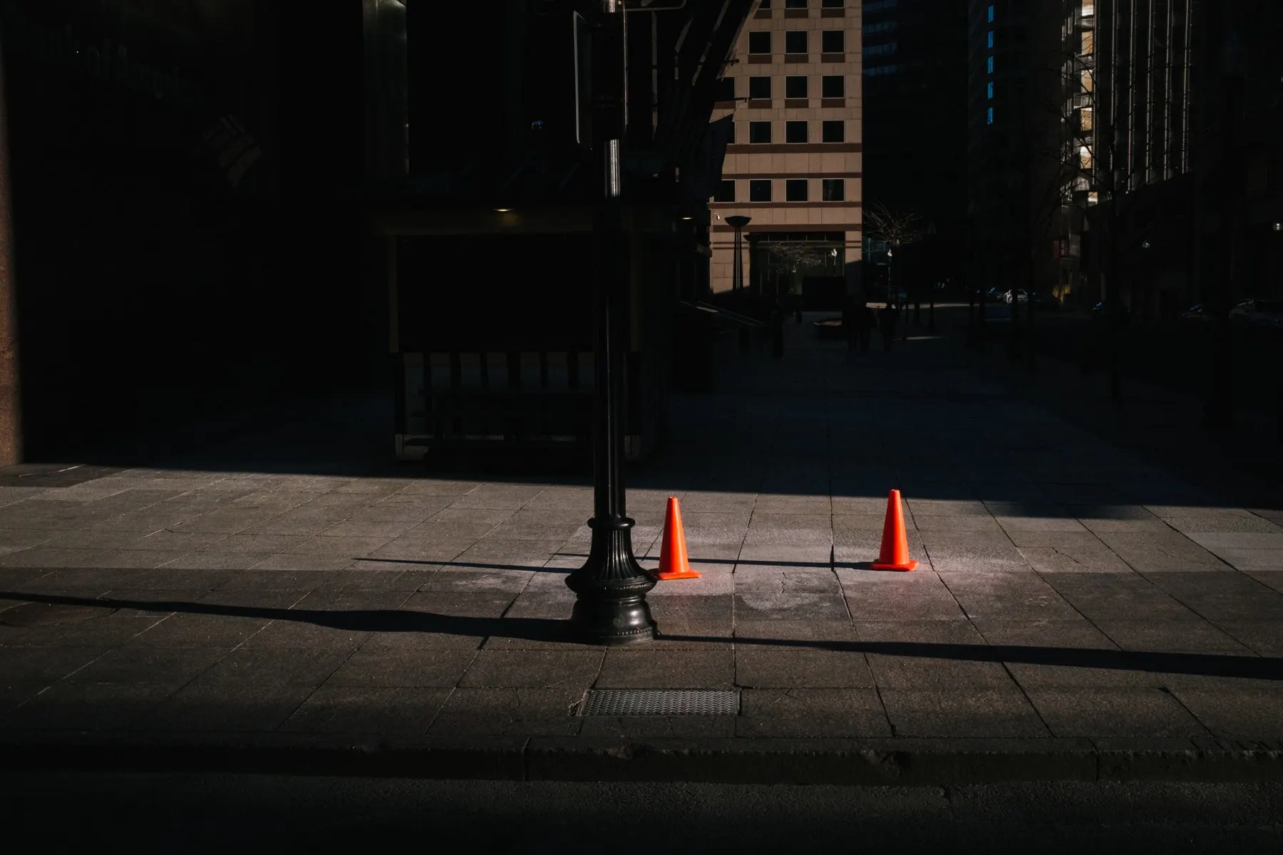 Two cones in a patch of light on a dark pavement