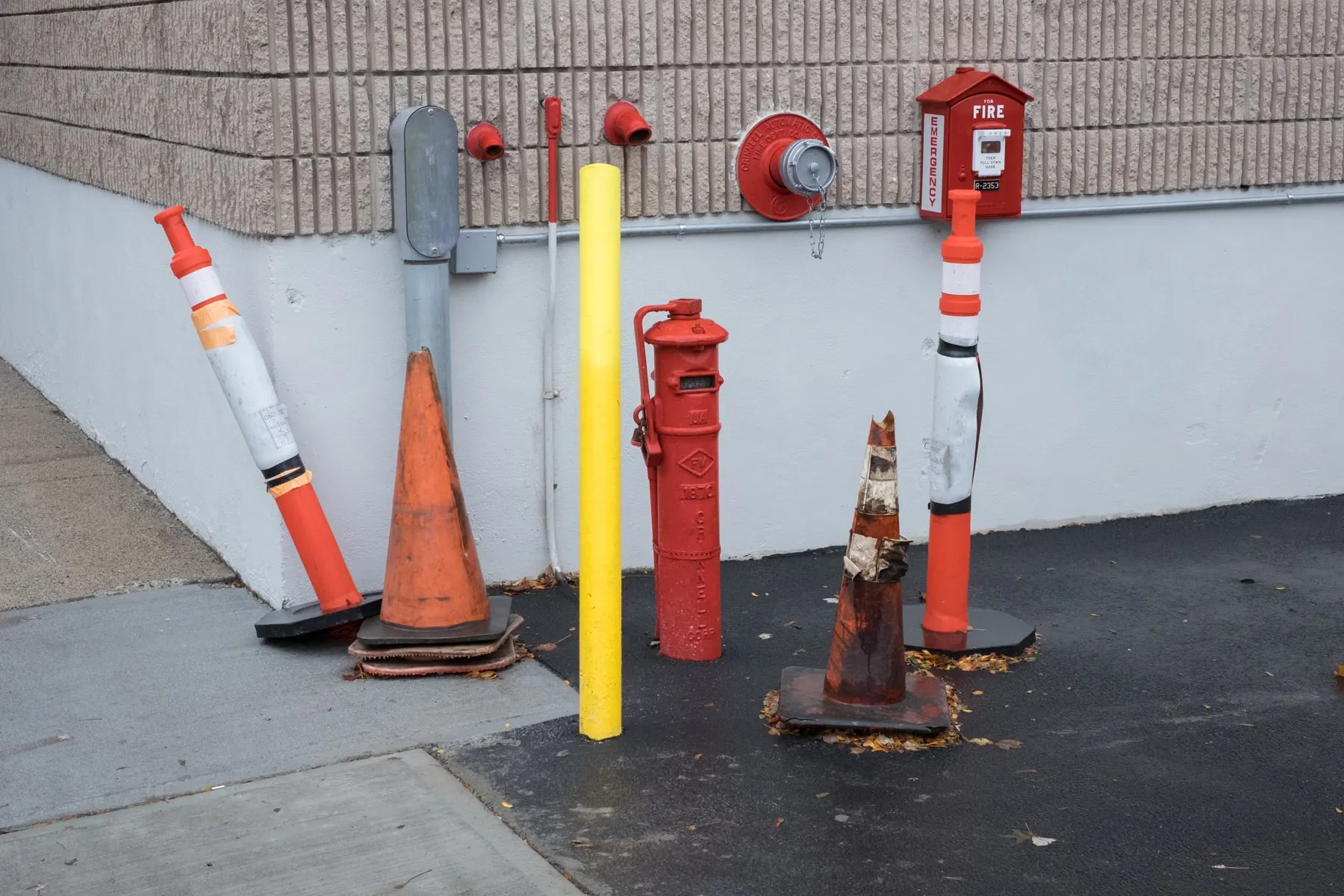 Cones, posts and a hydrant along a white wall